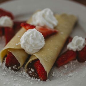 Freshly made strawberry crepes topped with whipped cream, perfect for a delightful breakfast or dessert.