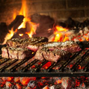 Succulent steaks grilling over hot coals and flames for a mouthwatering cookout.