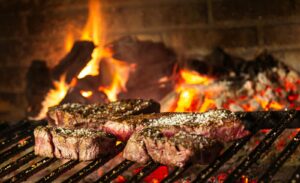 Succulent steaks grilling over hot coals and flames for a mouthwatering cookout.