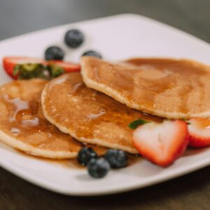 Mouth-watering pancakes topped with syrup and fresh berries, perfect for a wholesome breakfast.